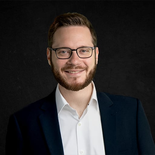 GBE Makler - Raphael Dreyer mit Brille, Bart und Anzug vor dunklem Hintergrund - professionelles Business-Foto für Finanzen, Beratung oder digitalen Handel